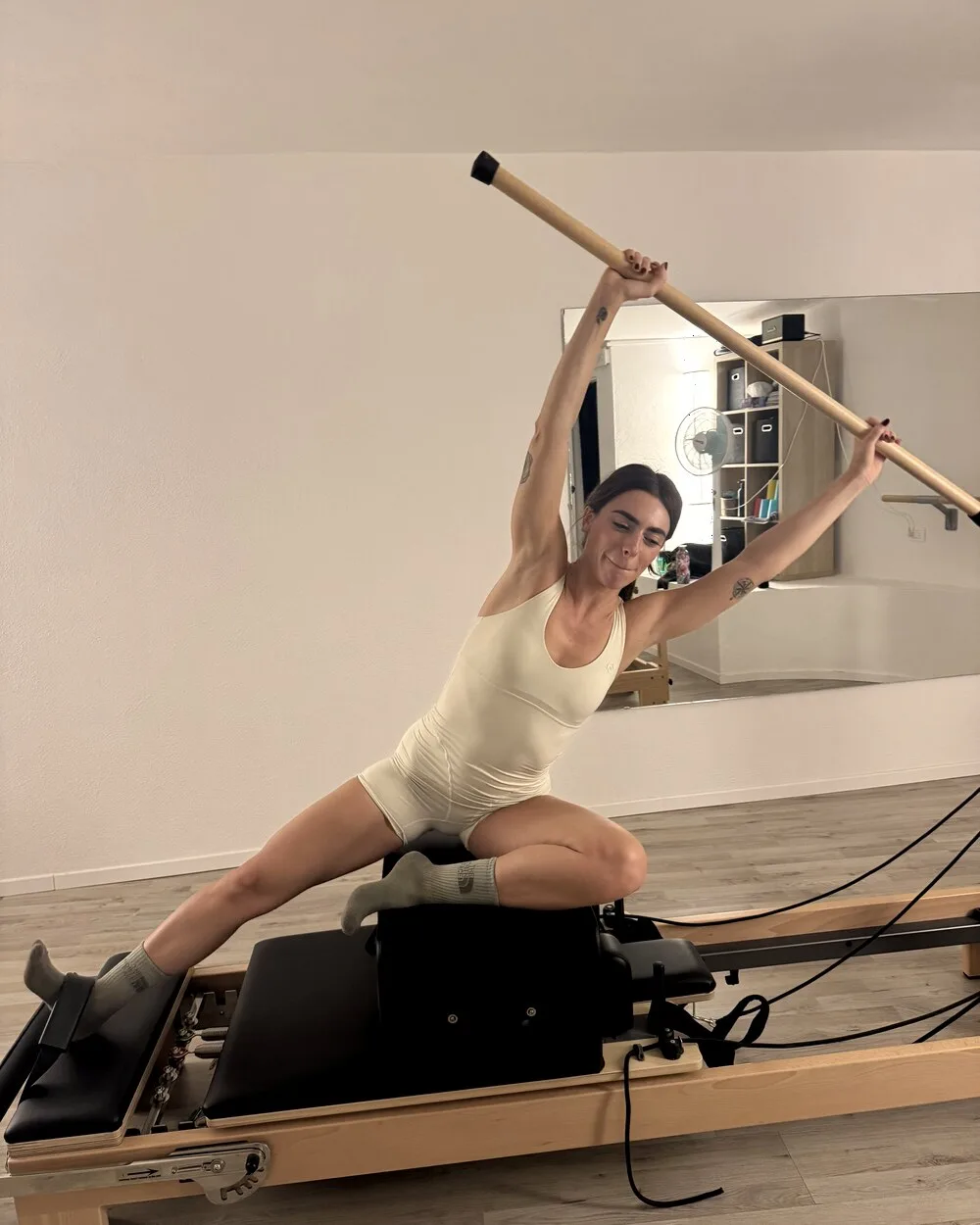 Client performing a mermaid side-stretch on the reformer